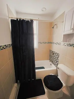 a bathroom with a black shower curtain and a toilet at 3 bdrm stay! Trippy King Suite by Dwtwn Nwk in Newark
