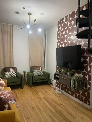 a living room with two green chairs and a flat screen tv at 3br 3bath Duplex NY 23 mins in Hoboken