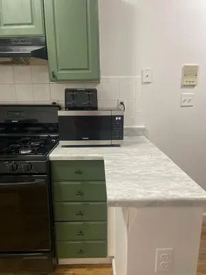 a kitchen with green cabinets and a black microwave at 3br 3bath Duplex NY 23 mins in Hoboken