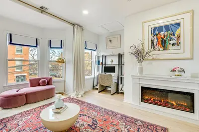 a living room with a fireplace and a pink couch at 1 Mi to Prudential Center Remote Work-Ready Apt in Newark