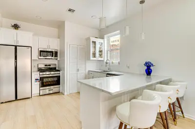 a white kitchen with white appliances and white cabinets at 1 Mi to Prudential Center Remote Work-Ready Apt in Newark