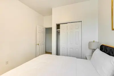 a white bedroom with a bed and a door at 1 Mi to Prudential Center Remote Work-Ready Apt in Newark