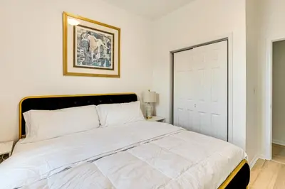 a bedroom with a large white bed with a door at 1 Mi to Prudential Center Remote Work-Ready Apt in Newark