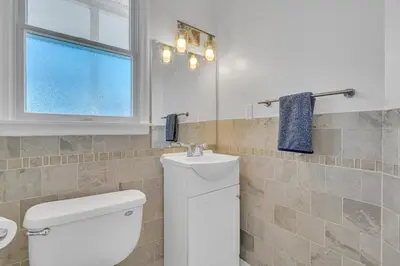 a bathroom with a white toilet and a window at Bayview Coastal Home - Steps to Shore & Free Parking in Keansburg