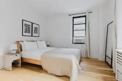 a white bedroom with a bed and a window at Blueground Midtown gym AC nr Chrysler NYC-1665 in New York