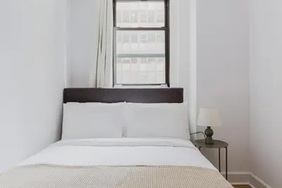 a white bed in a room with a window at Blueground Midtown gym AC nr Chrysler NYC-1665 in New York