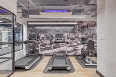 a gym with three treadmills and a painting on the wall at Blueground Midtown gym AC nr Chrysler NYC-1665 in New York