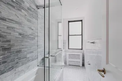 a white bathroom with a shower and a toilet at Blueground Midtown gym AC nr Chrysler NYC-1665 in New York