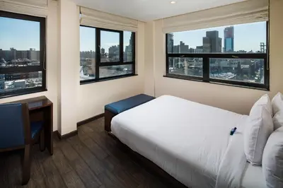 a bedroom with a bed and a desk and windows at Orchard Street Hotel in New York