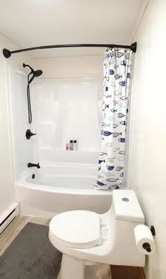 a white bathroom with a toilet and a bath tub at Pocono Cabin Fireplace Near Skiing Tubing Parks Shopping Casinos Hot Tub Walk to Lake in Pocono Lake