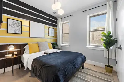 a bedroom with a large bed with yellow and white stripes at 1A Prime Area Near NYC and EWR 98 Walk score in Newark