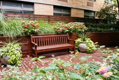 a wooden bench sitting in a garden with flowers at UWS 1br w gym doorman elevator nr Central Park NYC-1049 in New York