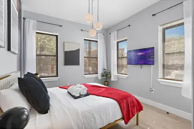 a bedroom with a bed with a red blanket and windows at 1C - Ask About 20Off - Sleeps 5 - Airport 8min - NYC 30min in Newark
