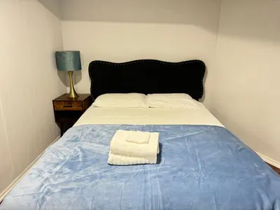 a bed with a blue blanket and a towel on it at Cozy 1 bedroom close to NYC with private bar in North Bergen
