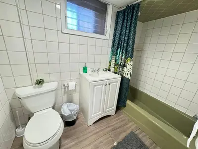 a bathroom with a toilet and a sink and a window at Cozy 1 bedroom close to NYC with private bar in North Bergen