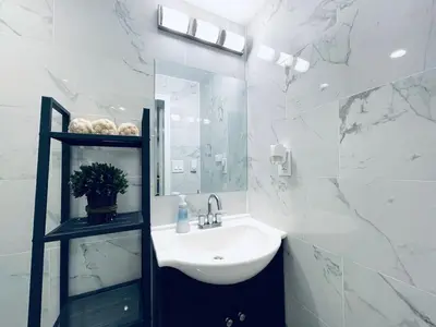 a white bathroom with a sink and a mirror at Luxe City Hall Suite by Rittenhouse Square in Philadelphia