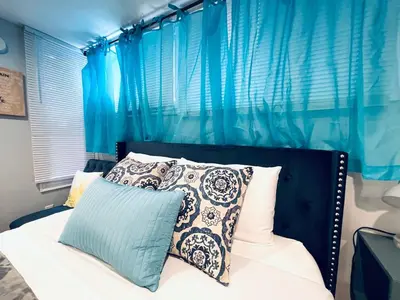 a bedroom with a bed with blue curtains and pillows at Luxe City Hall Suite by Rittenhouse Square in Philadelphia