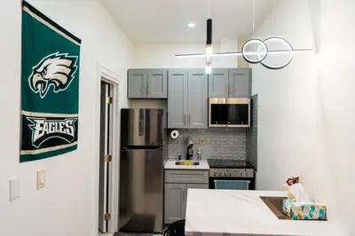 a kitchen with white cabinets and a green sign on the wall at New - Suite by Rittenhouse Square in Philadelphia