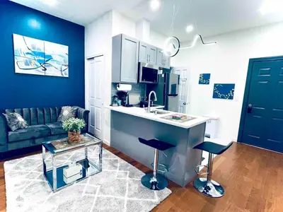 a kitchen with a sink and two stools in a living room at NEW - 1 Bedroom near Rittenhouse Square in Philadelphia