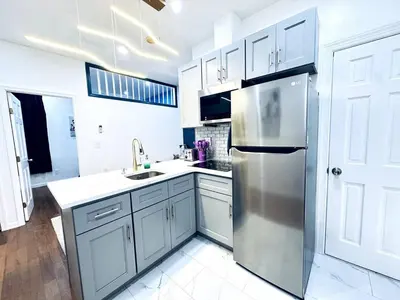 a kitchen with white cabinets and a stainless steel refrigerator at NEW - 1 Bedroom close by Rittenhouse Square in Philadelphia