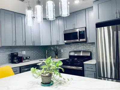 a kitchen with white cabinets and a table with a plant at Magic Gardens 2BD Apt in Center City in Philadelphia