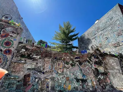 a wall covered in tiles with a tree in the background at Magic Gardens 2BD Apt in Center City in Philadelphia