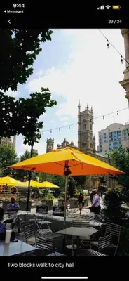 two tables and chairs under a yellow umbrella at Rittenhouse Square near Kimmel Center 1BD in Philadelphia