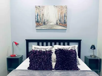 a bedroom with a bed with purple pillows and a painting at Rittenhouse Square near Kimmel Center 1BD in Philadelphia