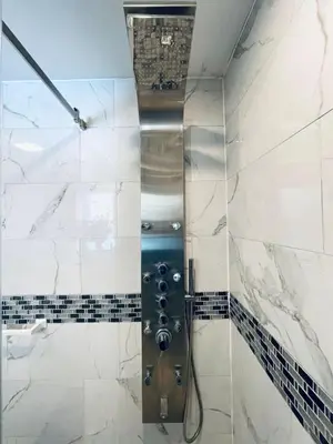 a shower in a bathroom with white tiles at Vibrant 1BD Suite in Downtown Center City in Philadelphia