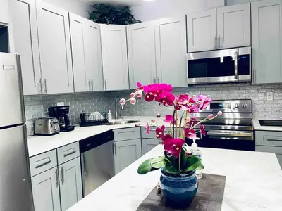 a kitchen with white cabinets and a vase with pink flowers at Lovely Beautiful 2BR Apt in Center City in Philadelphia