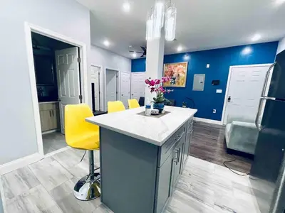 a kitchen with blue walls and a counter with yellow chairs at Lovely Beautiful 2BR Apt in Center City in Philadelphia