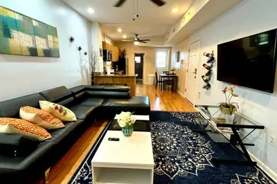 a living room with a black leather couch and a tv at Modern Home w. Deck in Passyunk Square in Philadelphia