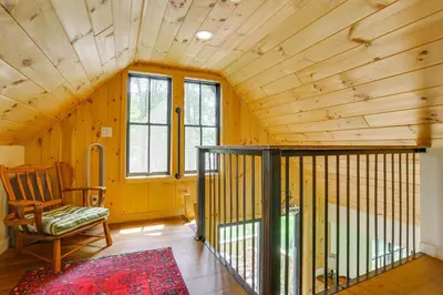 a room with a chair and a wooden ceiling at Waterfront Studio with Loft and Dock Near Narrowsburg! in Narrowsburg