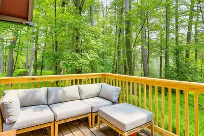 a porch with two couches on a deck with trees at Waterfront Studio with Loft and Dock Near Narrowsburg! in Narrowsburg