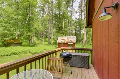 a porch with a grill and chairs on a deck at Waterfront Studio with Loft and Dock Near Narrowsburg! in Narrowsburg