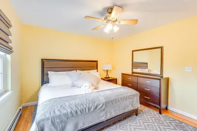 a bedroom with a bed with a ceiling fan and a mirror at 4 Mi to Hudson River Cozy Newburgh Home! in Newburgh