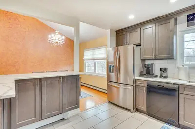 a kitchen with wooden cabinets and a stainless steel refrigerator at 4 Mi to Hudson River Cozy Newburgh Home! in Newburgh
