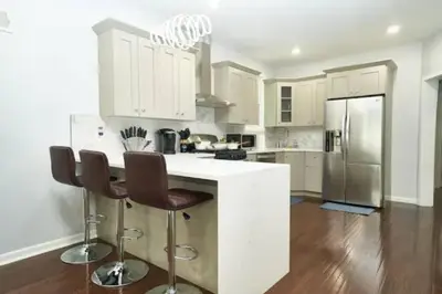 a kitchen with white cabinets and a kitchen island with bar stools at Music - Big 3br with King Bd Close to EWR and NYC in Bayonne