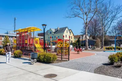 a man walking past a playground in a park at Music - Big 3br with King Bd Close to EWR and NYC in Bayonne