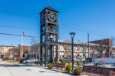 a black clock tower with a clock on it next to benches at Movie - 4 bedroom with King bed, deck and 80 in Movie Screen in Bayonne