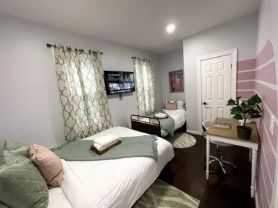 a bedroom with a bed and a desk with a tv at Duplex apt - Dining - 80in Projector - Pool Table in Bayonne