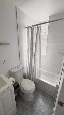 a white bathroom with a toilet and a shower at Beautiful Bedroom with Attached Bathroom, 15 minutes from NYC in West New York