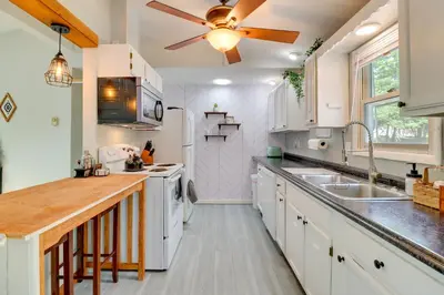 a kitchen with white cabinets and a ceiling fan at Community Pools and Hot Tub Albrightsville Cottage! in Albrightsville
