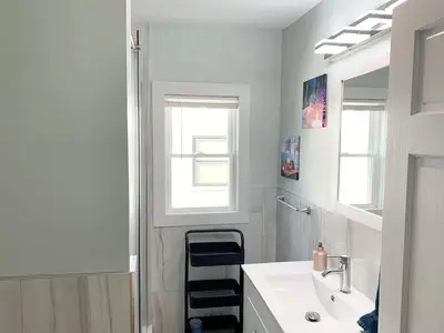 a white bathroom with a sink and a mirror at Newly Renovated 2 BR downtown Apt, family getaway. in Montclair