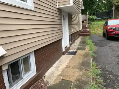 a house with a car parked next to a driveway at Semi Private cozy studio near downtown. in Montclair