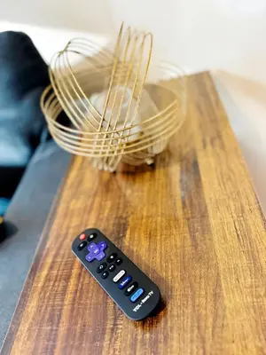 a remote control sitting on top of a wooden table at NYC 2 Bed America Dream Mall Train Station in Newark