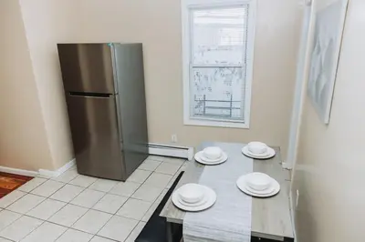 a kitchen with a stainless steel refrigerator and plates on a table at NYC 2 Bed America Dream Mall Train Station in Newark