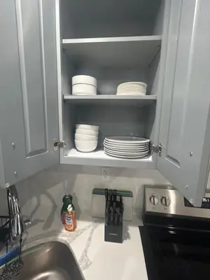 a kitchen counter with a sink and plates in a cabinet at Cozy 2-3 Bedroom Apartment in Center City! in Philadelphia