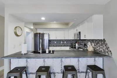 a kitchen with a counter with three stools and a refrigerator at The Hawley Nook at Lake Wallenpaupack in Hawley