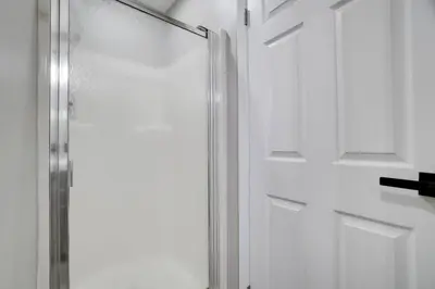 a glass shower door in a white bathroom at The Hawley Nook at Lake Wallenpaupack in Hawley
